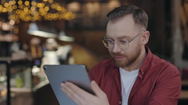 Programador digitando no tablet enquanto trabalhava no café. Homem usando gadget com sorriso. — Vídeo de Stock