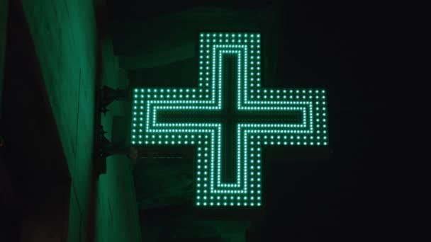 Pharmacy emblem flickers in the dark, lamps are lit on the street at night. — Stock Video