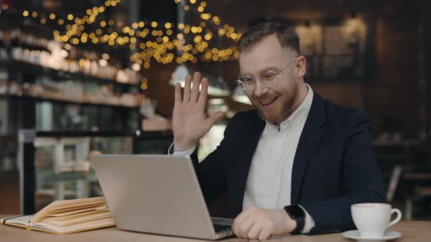 Επιχειρηματίας που χρησιμοποιεί φορητό υπολογιστή για σύνδεση βίντεο και χαιρετισμό. Ο άνθρωπος κάθεται στο καφέ. — Αρχείο Βίντεο