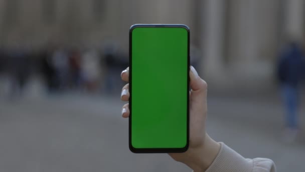 Vrouw vasthouden en aanraken telefoon met groen scherm verticaal in de straat. — Stockvideo