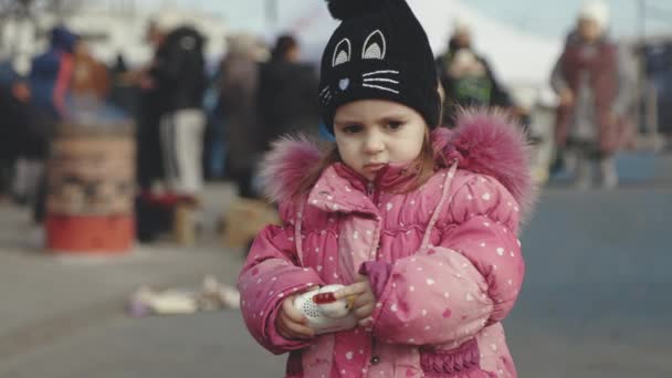 Lvov, Ukrajina - 15. března 2022: Portrét malé holčičky stojící na ulici. Evakuovaní z východní Ukrajiny v blízkosti železniční stanice v západním ukrajinském městě Lvově. — Stock video
