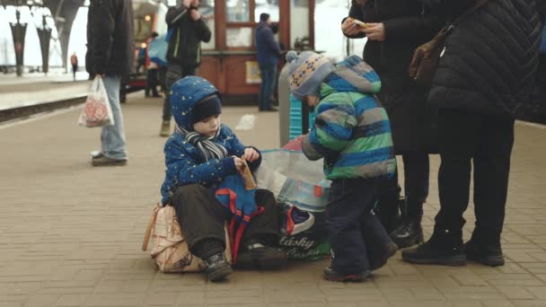 Lviv, Ucrânia - 15 de março de 2022: Retrato de duas crianças refugiadas da Ucrânia brincando na estação ferroviária. Guerra entre Ucrânia e Rússia conceito. — Vídeo de Stock