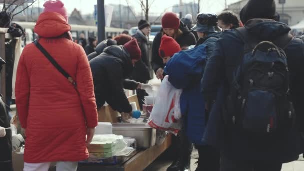 Lviv, Ucrânia - 15 de março de 2022: Voluntários dando comida e ajuda humanitária para as pessoas que fogem dos campos de batalha e deixam sua casa. Conceito de ajuda aos refugiados. — Vídeo de Stock