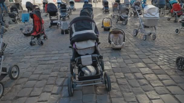 Lviv, Ukraina - 18 mars 2022: Tomma barnvagnar på Rynok-torget i Lviv symboliserar ukrainska barn som dödats sedan början av kriget mellan Ryssland och Ukraina. — Stockvideo