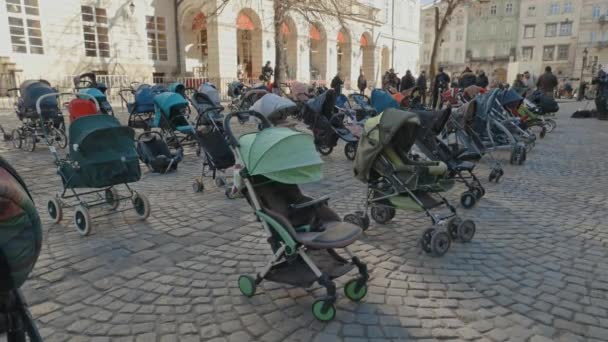 Lvov, Ukrajina - 18. března 2022: 109 prázdné kočárky na Rynokově náměstí ve Lvově symbolizují ukrajinské děti zabité od začátku rusko-ukrajinské války. — Stock video