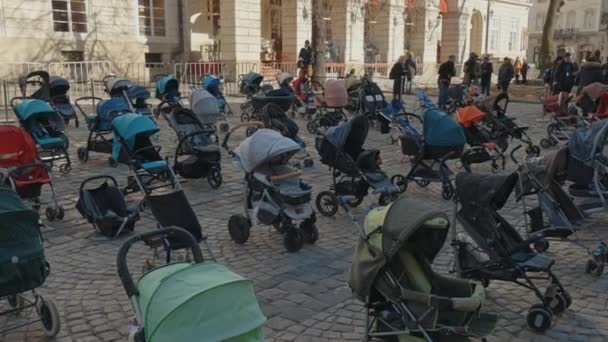 Lviv, Ukraina - 18 mars 2022: 109 tomma barnvagnar på Rynok Square i Lviv symboliserar ukrainska barn dödade sedan början av det rysk-ukrainska kriget. — Stockvideo