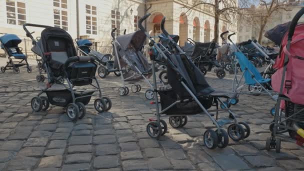 Lviv, Ukraina - 18 mars 2022: 109 tomma barnvagnar på Rynok Square i Lviv symboliserar ukrainska barn dödade sedan början av det rysk-ukrainska kriget. — Stockvideo