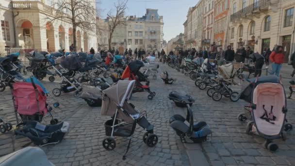 Lwów, Ukraina - 18 marca 2022: 109 puste wózki dziecięce na placu Rynok we Lwowie symbolizują ukraińskie dzieci zabite od początku wojny rosyjsko-ukraińskiej. — Wideo stockowe
