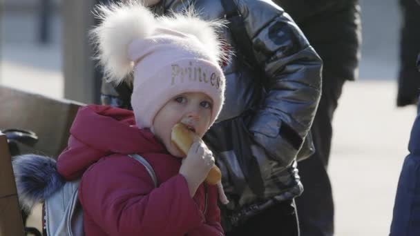 Lviv, Ukrayna - 15 Mart 2022 Sokakta yemek yiyen küçük bir kızın portresi. Ukrayna 'nın doğusundan, Ukrayna' nın tren istasyonu yakınlarından tahliye edilenler. — Stok video