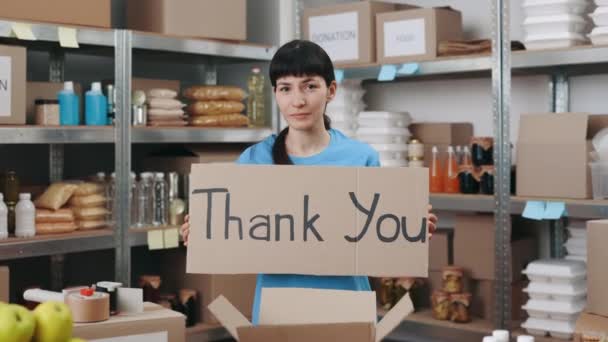 Mujer sosteniendo pancarta con frase gracias en el banco de alimentos — Vídeo de stock