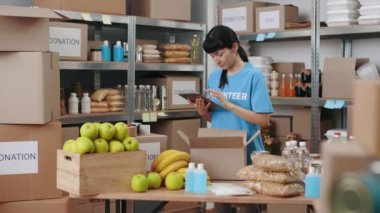 Kadın, yiyecek bankasındaki malzemeleri kontrol etmek için tablet kullanıyor.