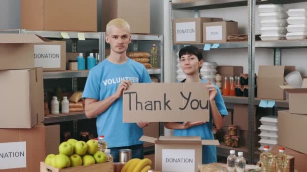 Добровольцы держат плакат с текстом спасибо в продовольственном банке — стоковое видео