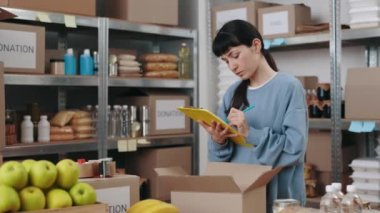 Elinde dosya olan bir kadın depoda gönüllü olarak çalışıyor.