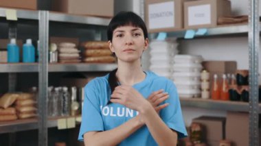 Kadın gönüllü depoda çapraz kollarla poz veriyor.