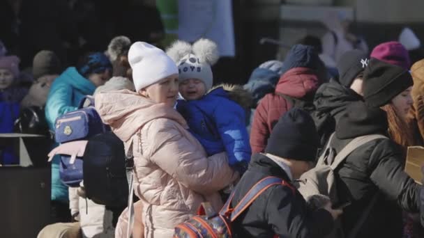 Lviv, Oekraïne - 15 maart 2022: Vrouw die haar huilende kind door de handen houdt en kalmeert. Oekraïense moeder en zoon vluchtelingen op station wachten op trein naar Europa te ontsnappen. — Stockvideo
