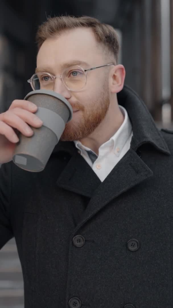 Vertikales Video des Geschäftsmannes, der in der Nähe eines Bürozentrums spaziert und Kaffee trinkt. — Stockvideo