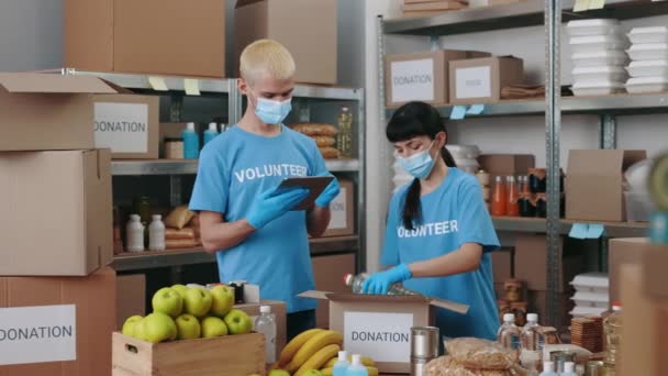 Gruppe von Freiwilligen packt Spendenboxen und verwendet Tabletten — Stockvideo