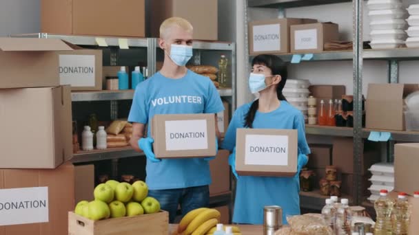 Equipo de voluntarios en máscaras faciales que sostienen cajas de donación — Vídeos de Stock