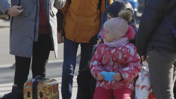 Lvov, Ukrajina - 15. března 2022: Portrét malé holčičky stojící na ulici. Evakuovaní z východní Ukrajiny v blízkosti železniční stanice v ukrajinském městě. — Stock video