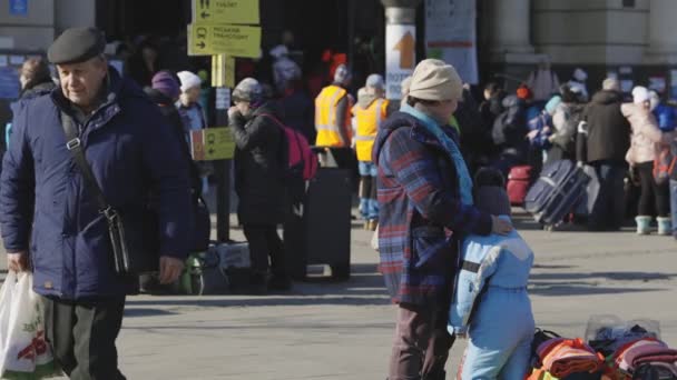 Lviv, Ukraine - 15 mars 2022 : Mère et fils ukrainiens réfugiés debout sur la gare de Lviv attendant que le train s'échappe vers l'Europe. Femme apaisant son enfant. — Video