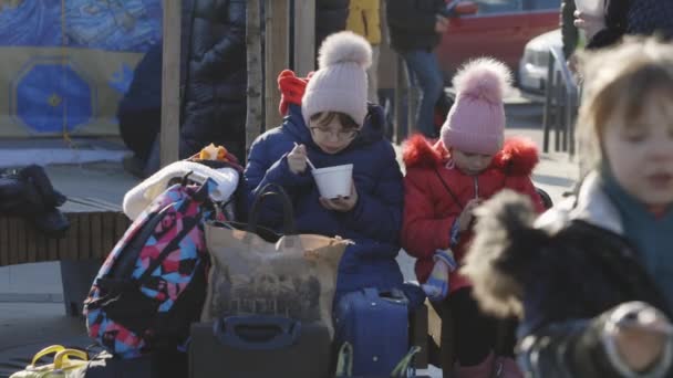 Lviv, Oekraïne - 15 maart 2022: Kind zit op het station en eet op straat tijdens de evacuatie uit Oekraïne. Oekraïense vluchtelingen. Oorlog. Rusland viel Oekraïne concept aan. — Stockvideo