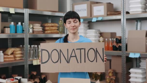 倉庫で単語寄付でバナーを保持する女性 — ストック動画