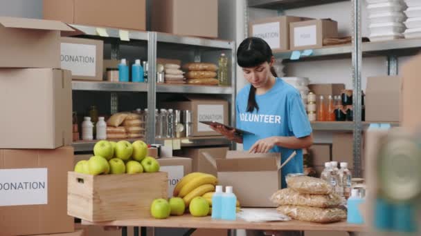 Žena dobrovolnice pracující v potravinové bance s digitálním tabletem — Stock video