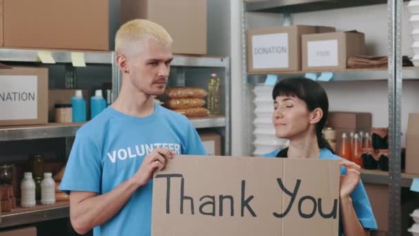 Voluntarios de pie en el almacén con banner de agradecimiento — Vídeo de stock