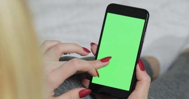 Weibchen schiebt grünen Chroma-Keyscreen mit Finger auf ihr Smartphone-Gerät. — Stockvideo