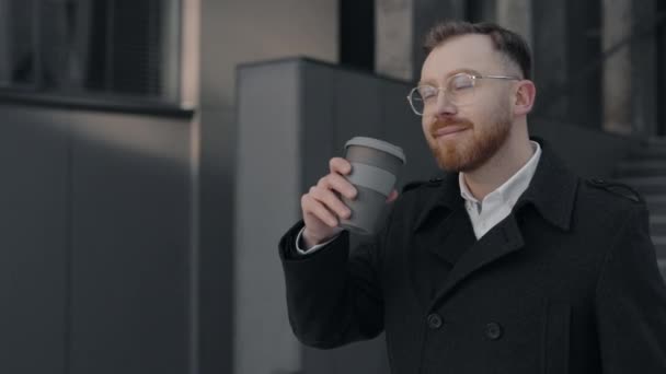 Biznesmen trzymający filiżankę kawy w dłoniach i pijący ją z uśmiechem. — Wideo stockowe