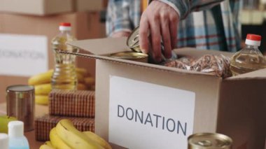 Depo çalışanları bağış kutularına yiyecek koyuyorlar.