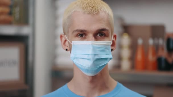 Портрет человека в маске, позирующего на складе продовольственного банка — стоковое видео