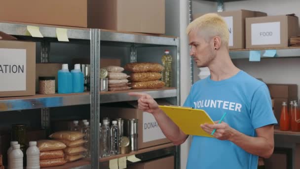 Dobrovolník si dělá poznámky při kontrole zásob v potravinové bance — Stock video
