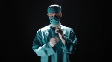 Cerrah koruyucu eldiven giyerken izole edilmiş arka planda poz veriyor..