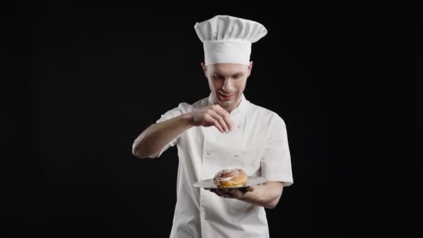 Portret van de mannelijke kok die naar de camera kijkt en het dessert besprenkelt. — Stockvideo