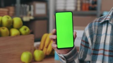 Yemek bankası çalışanı elinde akıllı telefon ile ekranı düzenliyor.