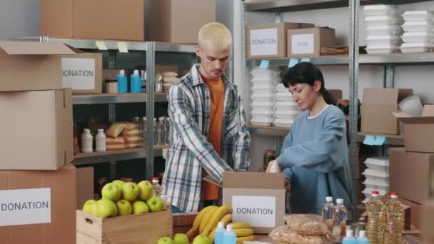 Tým dobrovolníků balí potraviny do krabic na dárcovství — Stock video