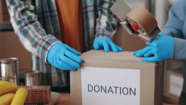Крупный план работников продовольственного банка в перчатках, упаковывающих коробки — стоковое видео