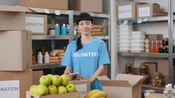 Femme en t-shirt bénévole posant à la banque alimentaire — Video