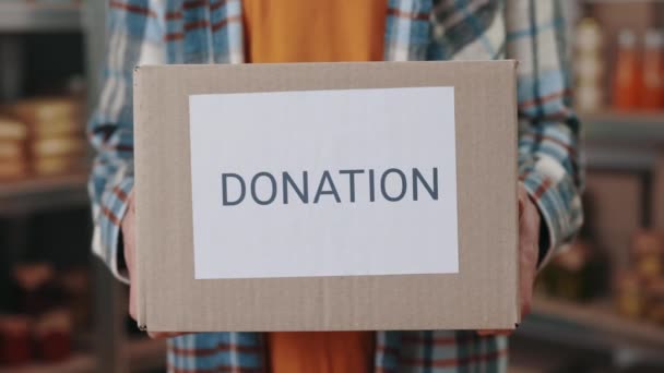 Close up of male hands holding donation box among storage — Stock Video