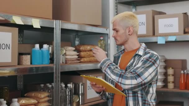 Homem escrevendo na área de transferência enquanto se voluntariava no banco de alimentos — Vídeo de Stock