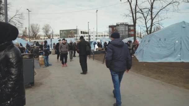 Львов, Украина - 15 марта 2022 года: Беженцы из Украины идут рядом с палатками с помощью волонтеров. Еда и другая помощь для людей в палатках после ухода из дома. Концепция помощи беженцам. — стоковое видео