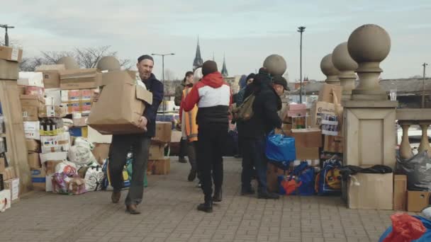 Lviv, Ukraine - March 15, 2022: Refugees from Ukraine unload humanitarian aid with volunteers. A lot of food and another help for people. People holding cupboard boxes. — Stock Video
