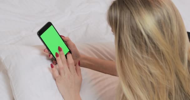 Evdeki yatakta yeşil ekranlı akıllı telefon kullanan bir kadın.. — Stok video