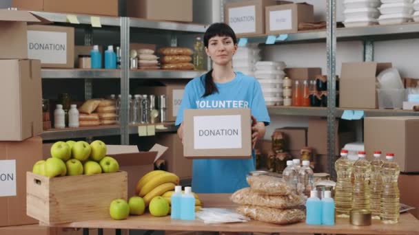 Femme debout à la banque alimentaire et tenant boîte de don — Video