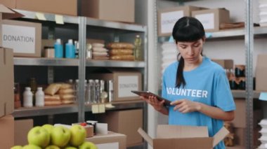 Kadın dijital tabletle yemek deposunda duruyor.