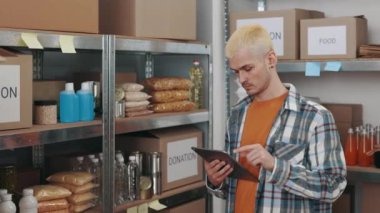 Yiyecek deposunu incelerken tablet kullanan bir adam.
