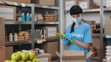 Depoda pano kullanarak yüz maskesi takan kadın yardım görevlisi