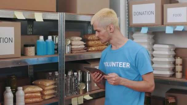 Pria hipster bekerja pada tablet saat memeriksa bank makanan — Stok Video