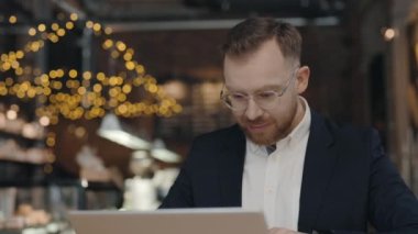 İş adamı kafede oturuyor ve dizüstü bilgisayarında bir şeyler yazıyor. İş konsepti